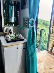 a kitchen with a blue curtain next to a window at La novia Del Mar un Cocon entre Ciel et Mer in Saint-Pierre +44 photos