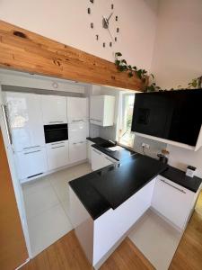 uma cozinha com armários brancos e um balcão preto em APARTAMENT LOFT z ANTRESOLĄ w GDAŃSKU em Gdansk
