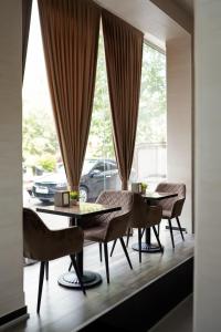 葉瑞文的住宿－Good Hotel Yerevan，一间带2张桌子和椅子的用餐室以及窗户。