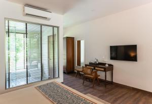 a living room with a desk and a television on a wall at Oleander Farms, Karjat in Karjat