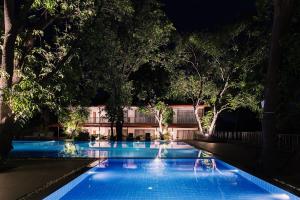 a swimming pool at night with trees and a building at Oleander Farms, Karjat in Karjat