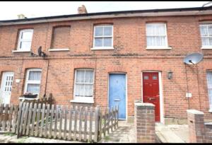 a brick house with two blue doors and a fence at Vetrelax Colchester 3bedroom house in Colchester