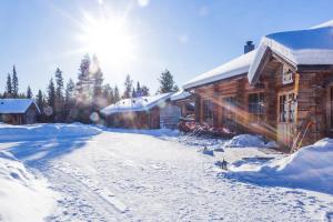 una carretera cubierta de nieve junto a una cabaña de madera en Basecamp Oulanka, en Ruka