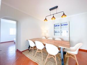 uma sala de jantar com uma mesa de madeira e cadeiras brancas em Ocean's Eye Sea view, 200m from the beach em Lagos