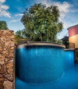 a blue swimming pool with a tree in the background at Kallisti Hotel in Potos