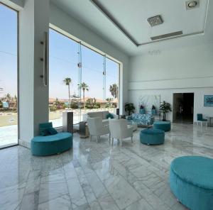 - un hall avec des sièges bleus et de grandes fenêtres dans l'établissement Golden Palace Marina Hotel, à El Alamein