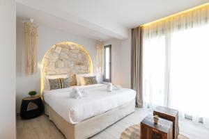 a bedroom with a large bed and a large window at Amalthia Luxury Suites in Polykhrono