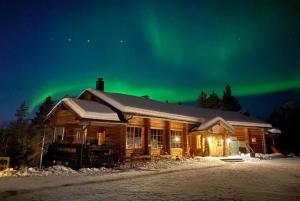 una cabaña de madera con la aurora en el cielo en Basecamp Oulanka, en Ruka