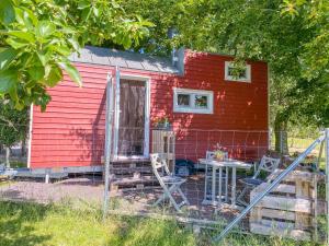 Rubkow的住宿－Tiny House auf der Alpaka Farm，前面有一张桌子和椅子的红色房子
