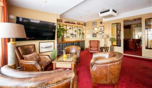 un soggiorno con sedie in pelle e TV a schermo piatto di Strandhotel de Vassy a Egmond aan Zee