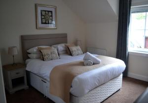 1 dormitorio con 1 cama grande con sábanas y almohadas blancas en Orangewood House, en Killin