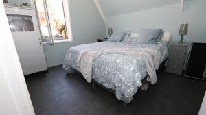 a bedroom with a bed with a blue comforter at !!!UNIEK!!! Rijksmonument centrum Harlingen in Harlingen