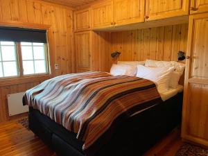a bedroom with a bed with a striped blanket on it at Kultan in Åmotsdal