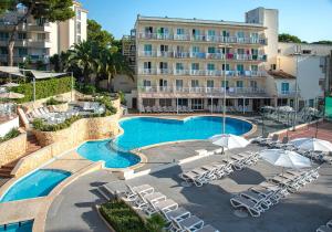 una piscina con sillas y sombrillas frente a un hotel en Club Hotel Cala Ratjada, en Cala Ratjada