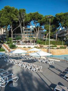 una fila de sillas y sombrillas junto a una piscina en Club Hotel Cala Ratjada, en Cala Ratjada