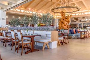 a restaurant with tables and chairs and a chandelier at Ikaros Beach, Luxury Resort & Spa in Malia
