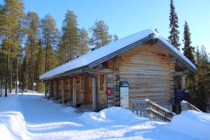 una cabaña de madera en la nieve con nieve en Basecamp Oulanka, en Ruka