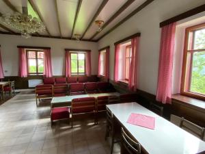 una sala de espera con sillas rojas, mesas y ventanas en Chata Botas, en Strážné