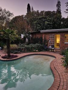 a swimming pool in a yard with a brick house at UppaTree Cottage in Benoni