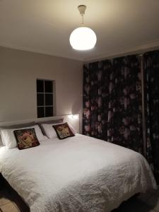 a bedroom with a large white bed with two pillows at UppaTree Cottage in Benoni