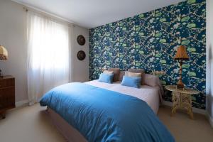 Schlafzimmer mit einem Bett mit blauen und grünen Tapeten in der Unterkunft Casa Palomera - Casa completa con jardín, gimnasio y garaje privados in León