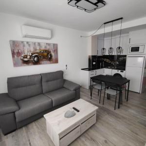 ein Wohnzimmer mit einem Sofa und einem Tisch in der Unterkunft Apartamentos Sol y Luna Conil in Conil de la Frontera