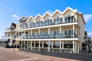 a large white building with balconies on a street at Strandhotel de Vassy in Egmond aan Zee