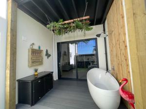 a bathroom with a bath tub and a flamingo in it at Coastline Retreats - Brand New Jungle Themed Garden Apartment - Outdoor Bath - Next to Seafront - Childrens Toys - Superfast Wifi - Netflix - Disney in Southbourne