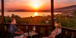 a man and a woman sitting at a table watching the sunset at Kallisti Hotel in Potos