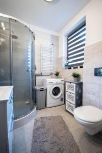 a bathroom with a shower and a washing machine at Pod Brzozami - domek nad jeziorem Białym in Orchówek