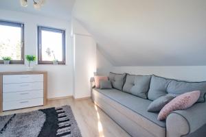 a living room with a gray couch and a dresser at Pod Brzozami - domek nad jeziorem Białym in Orchówek