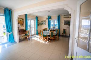a dining room and living room with blue curtains at Villa Can Pere Cala Galdana Menorca in Cala Galdana