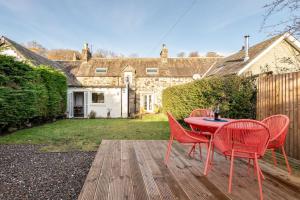 a red table and chairs on a wooden deck at Charming Cardoon Cottage in beautiful village in Comrie