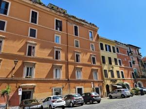 a large orange building with cars parked in front of it at Giulia Apartment in Trastevere in Rome