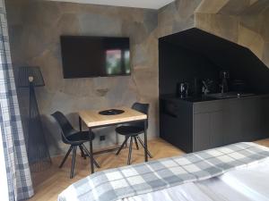 1 dormitorio con mesa pequeña y TV en la pared en Apartamenty BENITA, en Zakopane