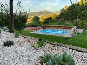 a swimming pool in a garden with rocks around it at Casinha à Porta in Arouca