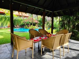 Una mesa y sillas en un patio con una mesa y una piscina. en SaffronStays Kimaya, Alibaug, en Alibaug