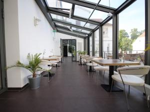 a dining room with tables and chairs and windows at Hotel am Schlosspark Superior in Putbus