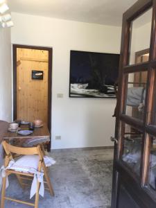 Habitación con mesa, TV y puerta. en Garola Coccodè 2, en Luserna San Giovanni