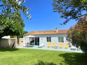 Casa blanca con sillas amarillas y patio en Maison Thalaos, en La Flotte