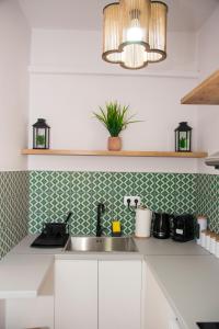 a kitchen with white cabinets and a sink and a lamp at Siroa Easy in Ermoupoli