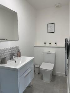 a white bathroom with a toilet and a sink at Central, Chic Apartment in Bournemouth