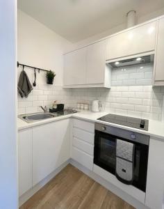 a white kitchen with a sink and a stove at Central, Chic Apartment in Bournemouth