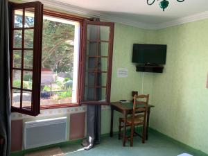 Zimmer mit einem Tisch, einem TV und einem Fenster in der Unterkunft Le Richelieu in Saint-Jean-de-Monts