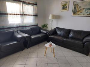 a living room with black leather couches and a table at LARA & VITO in Metajna