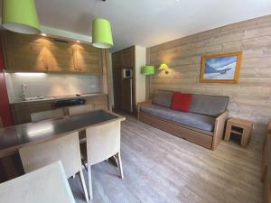 a living room with a couch and a kitchen at Appartement Centre Skis aux Pieds, Parking & Animaux Acceptés - FR-1-513-77 in La Tania