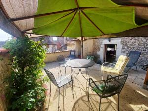 a patio with a table and chairs and an umbrella at Maison Le Troubadour in Ribérac