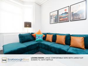 un sofá azul con almohadas naranjas en la sala de estar. en Scarborough Stays - Trafalgar Lodge - 4 bedroomed house - Free Parking en Scarborough