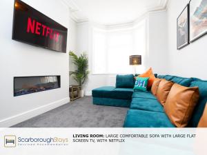 a living room with a blue couch and a tv at Scarborough Stays - Trafalgar Lodge - 4 bedroomed house - Free Parking in Scarborough