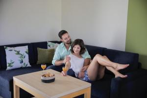Ein Mann und eine Frau sitzen auf einer Couch mit Weingläsern in der Unterkunft Barack Thermal & Natura Apartments in Tiszakécske